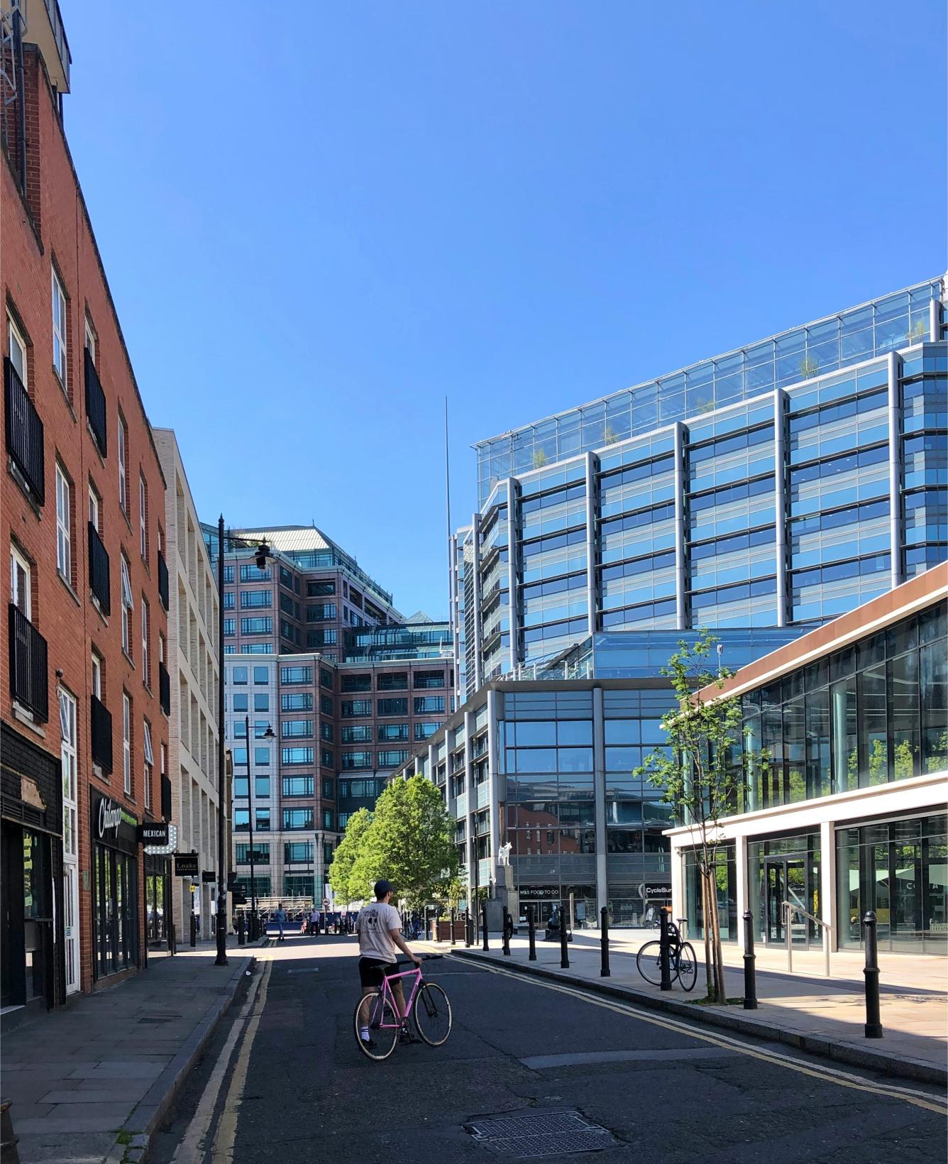 Man walking bicycle down street towards Spitalfields